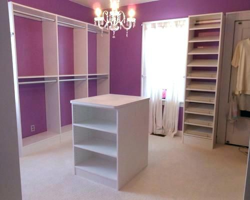 an empty closet with purple walls and white shelving unit in the center, chandelier hanging from the ceiling