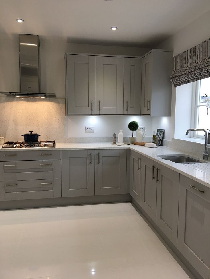 a kitchen with gray cabinets and white counter tops