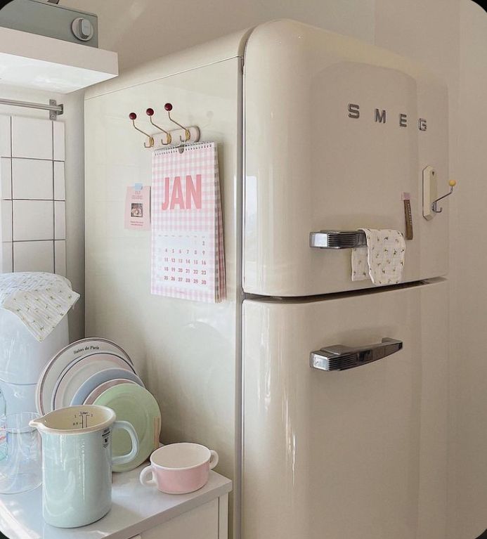 a white refrigerator freezer sitting inside of a kitchen next to a table with plates and cups on it