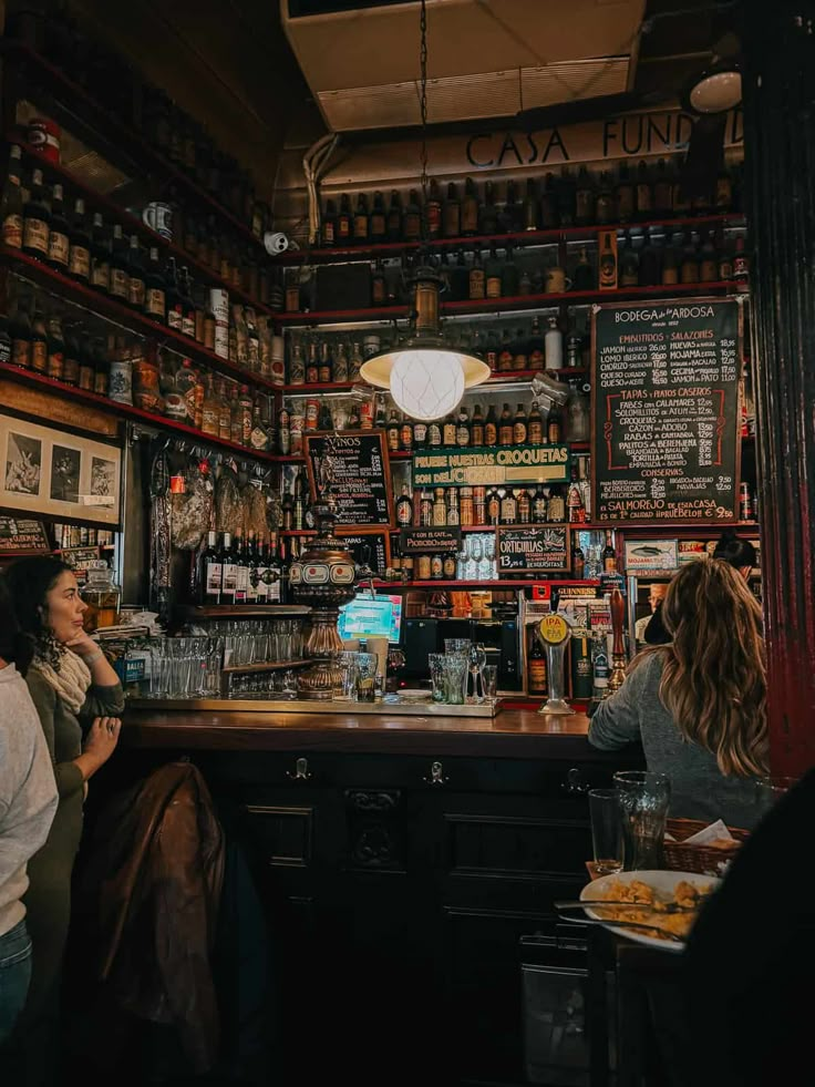 two women sitting at a bar talking to each other in front of the bar counter