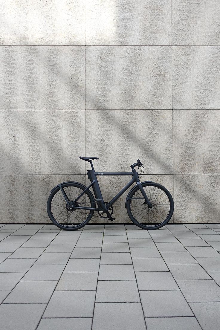 a bike is parked against a wall in front of a brick floored area with grey tiles