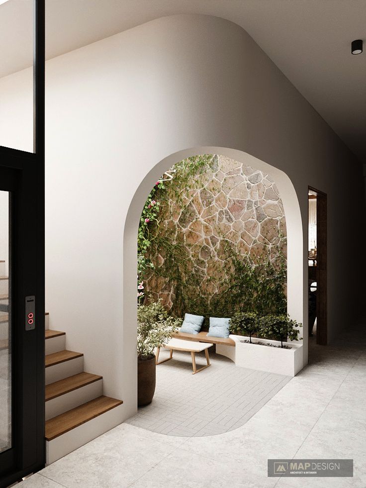 an arch leading into a living area with stairs and potted plants on either side