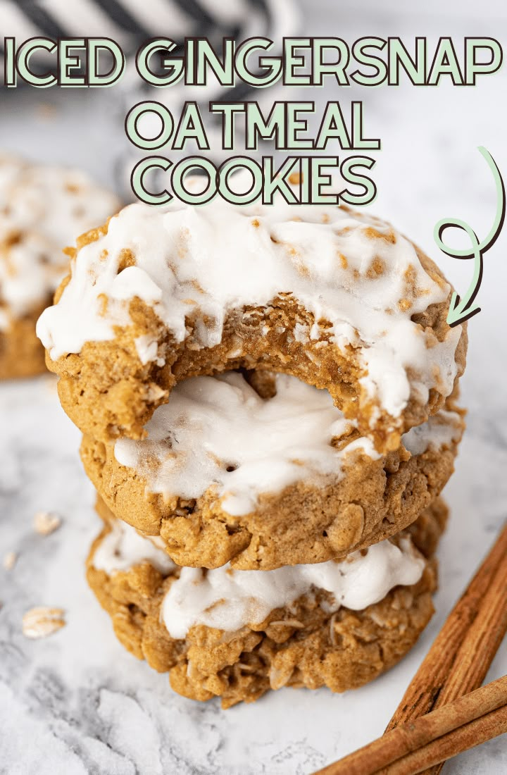 three cookies with icing and cinnamon sticks on a marble countertop next to two cinnamon sticks