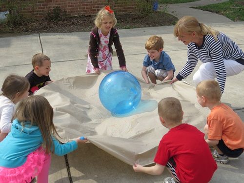 children playing with an inflatable ball on the ground and around the world sign