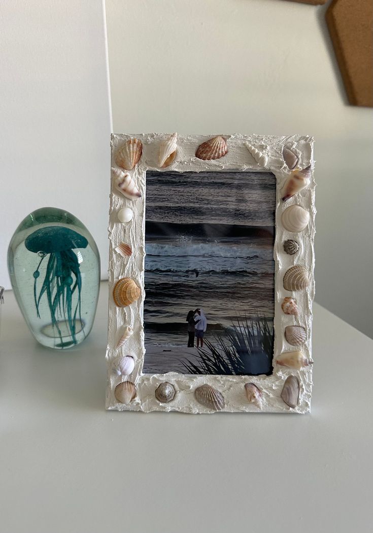 there is a photo frame with sea shells on it and a jellyfish in the background