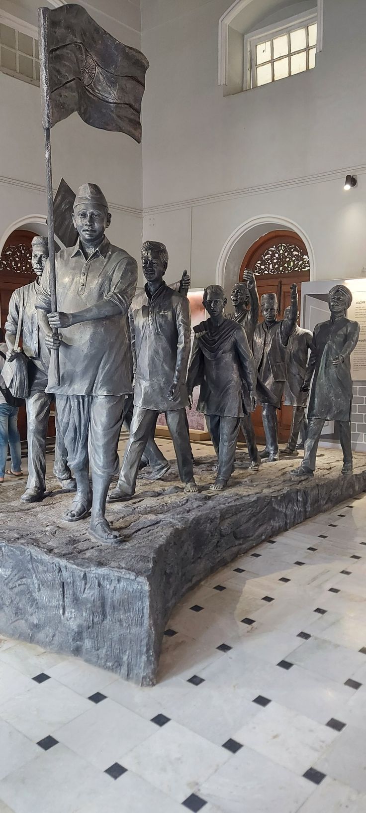 a group of people standing around a statue with a flag on it's head