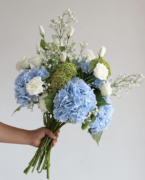 a person holding a bouquet of blue and white flowers