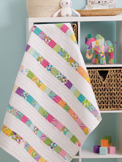 a baby quilt is hanging on the wall next to a bookcase and toy elephant