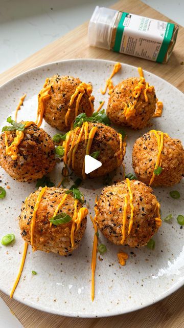 a white plate topped with meatballs covered in cheese and green onions on top of a wooden table