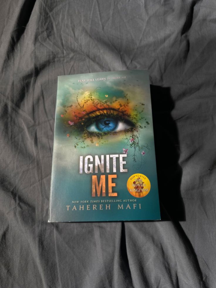 the book ignite me by tameeh mafi is laying on a gray sheet