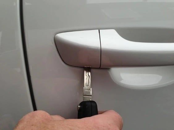 a hand holding a car door handle with a key in it