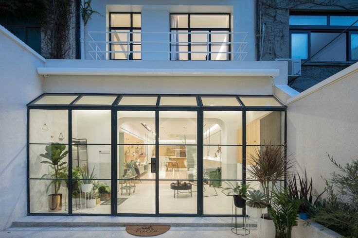 the entrance to a modern home with glass doors and plants in pots on the patio