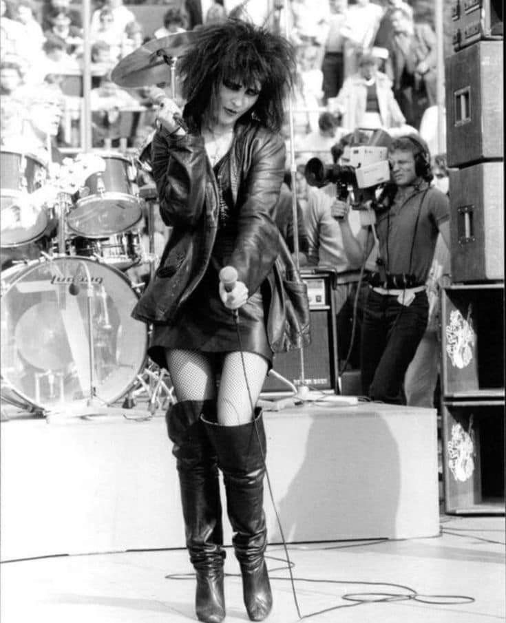 a woman in high boots is holding a microphone