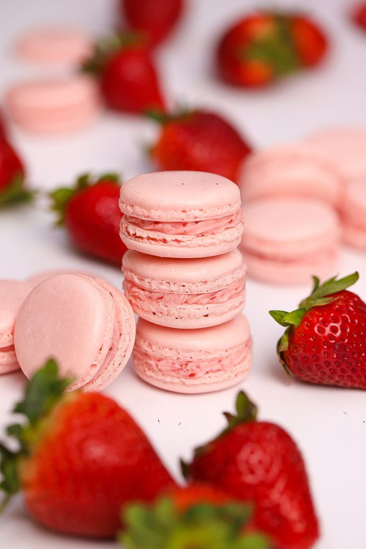 pink macaroons and strawberries on a white surface