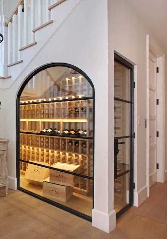 a wine cellar in the corner of a room with stairs leading up to an upstairs stair case