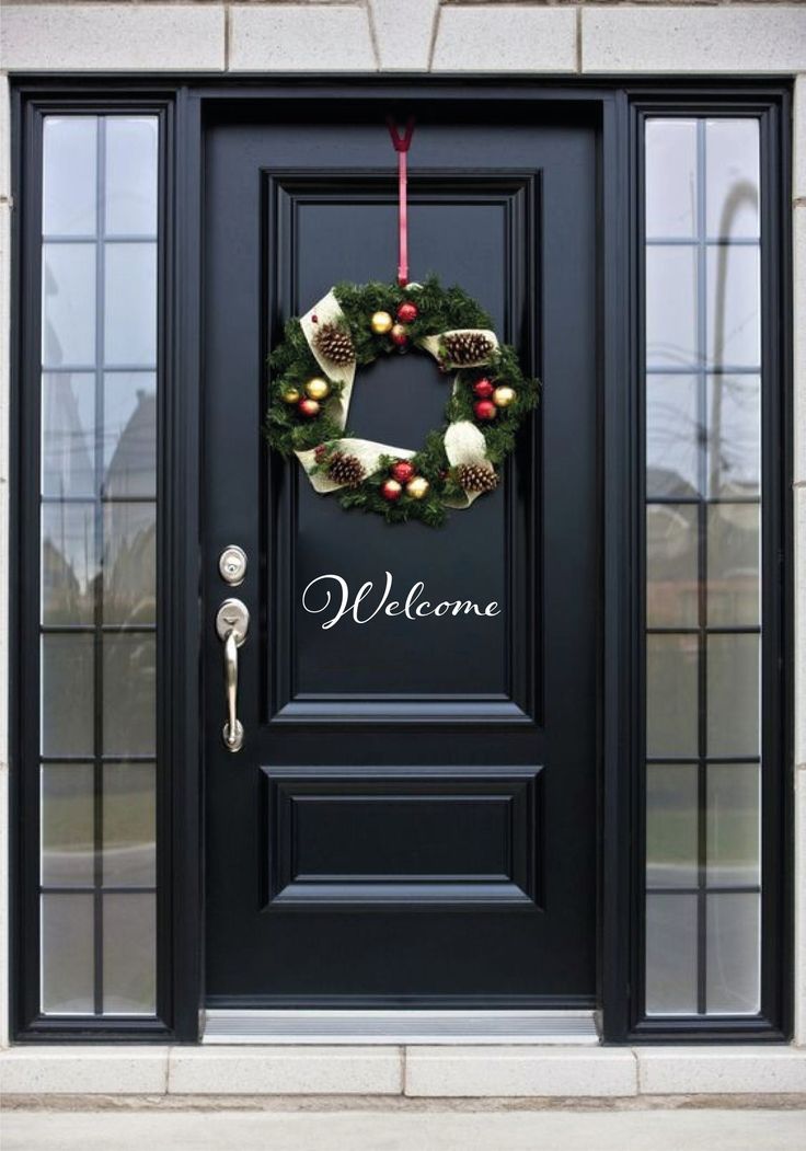 a black front door with a wreath and christmas decorations hanging on it's side