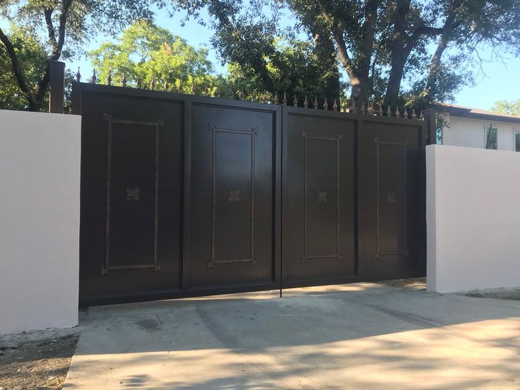 a gated in area next to a white wall and trees on the other side