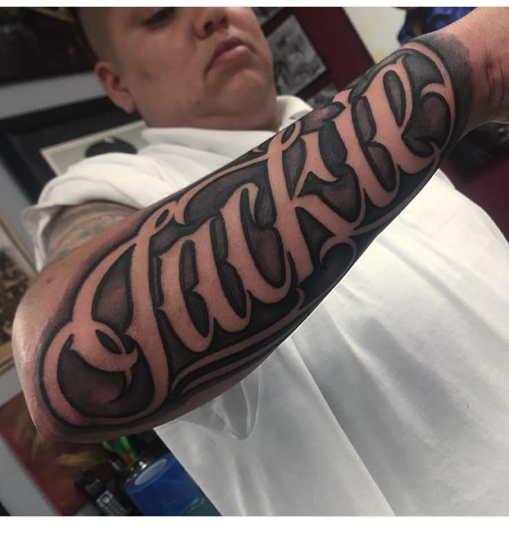 a man's arm with the word tattoo on it in black and grey ink