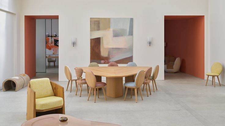 a dining room table with chairs and a painting on the wall in the back ground