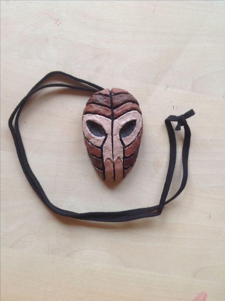 a wooden mask is sitting on a black cord