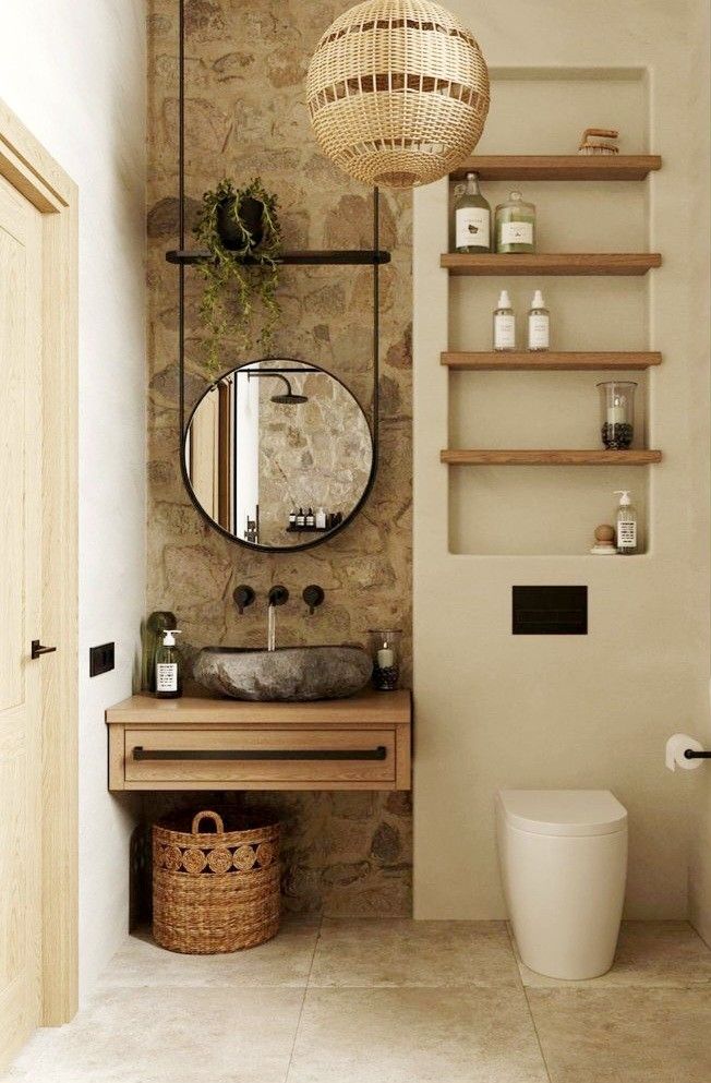 a bathroom with stone walls and a round mirror on the wall, above a sink