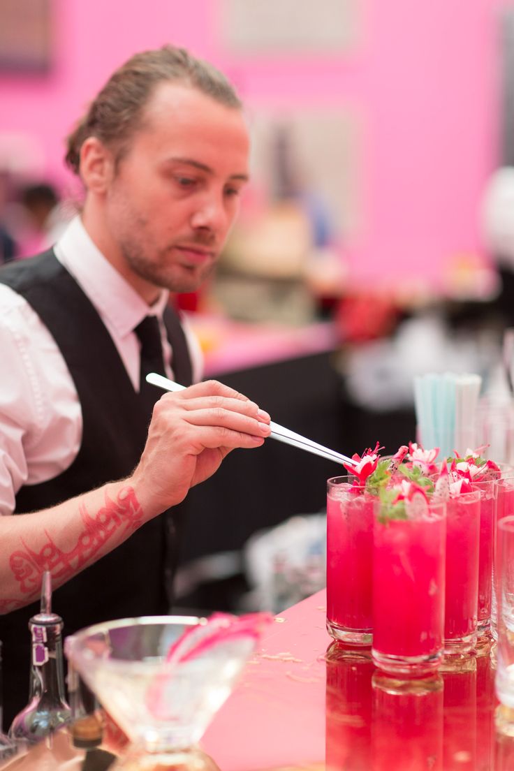 a man with tattoos on his arm is holding a straw in front of some drinks