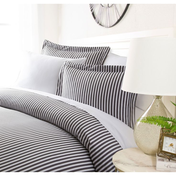 a bed with black and white striped bedspread next to a clock on the wall