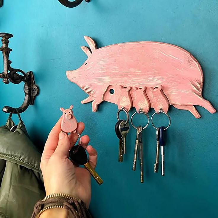 a person holding keys to a pig shaped key holder on a wall next to other items