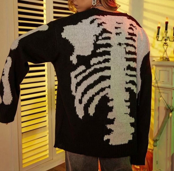 a woman standing in front of a window wearing a skeleton sweater