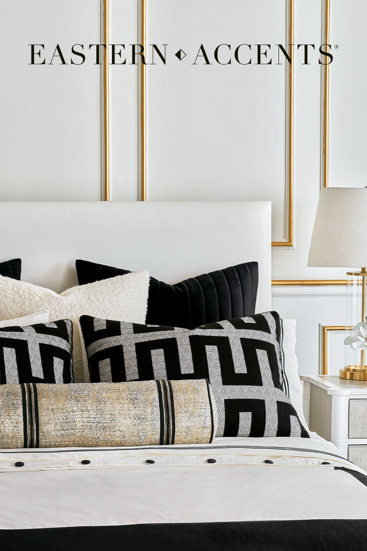 a bed with black and white pillows in front of a wall that says eastern accents