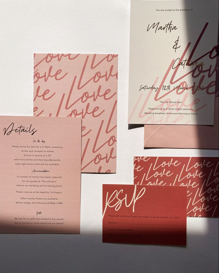 the wedding stationery is laid out on top of each other, including pink and red cards