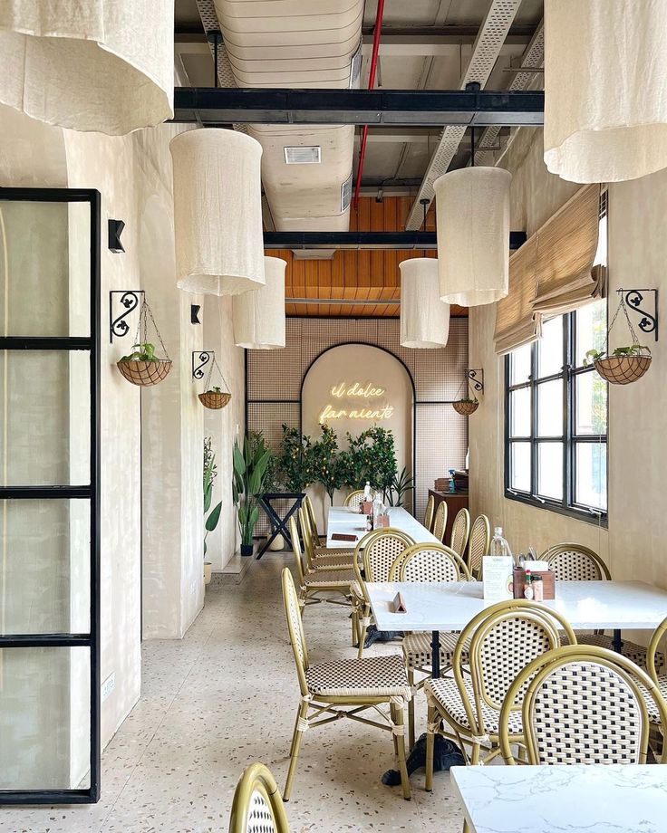 an empty restaurant with tables and chairs in the middle, hanging from the ceiling above