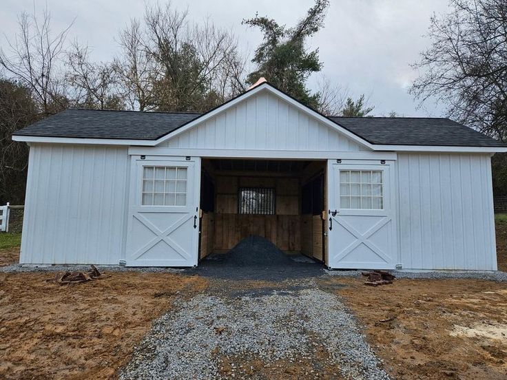 a white barn with an open door on the side