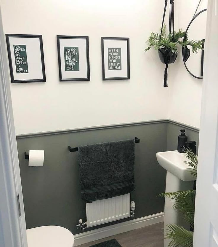 a white toilet sitting next to a sink in a bathroom under three framed pictures on the wall