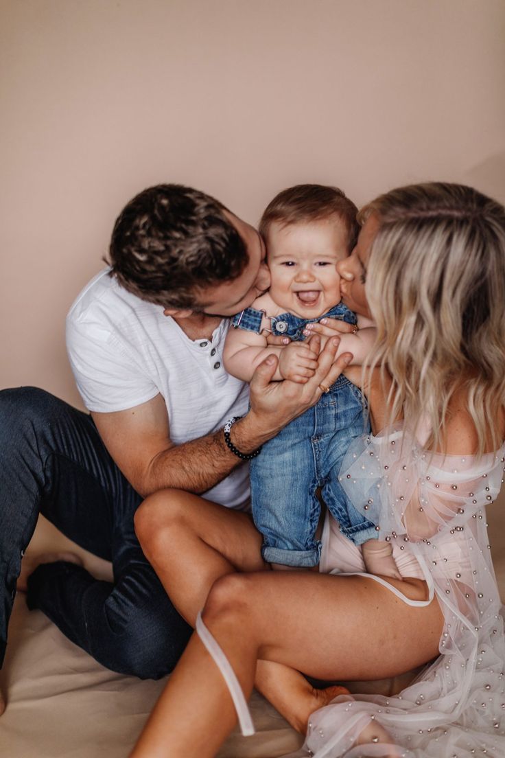 a man and woman holding a baby in their lap