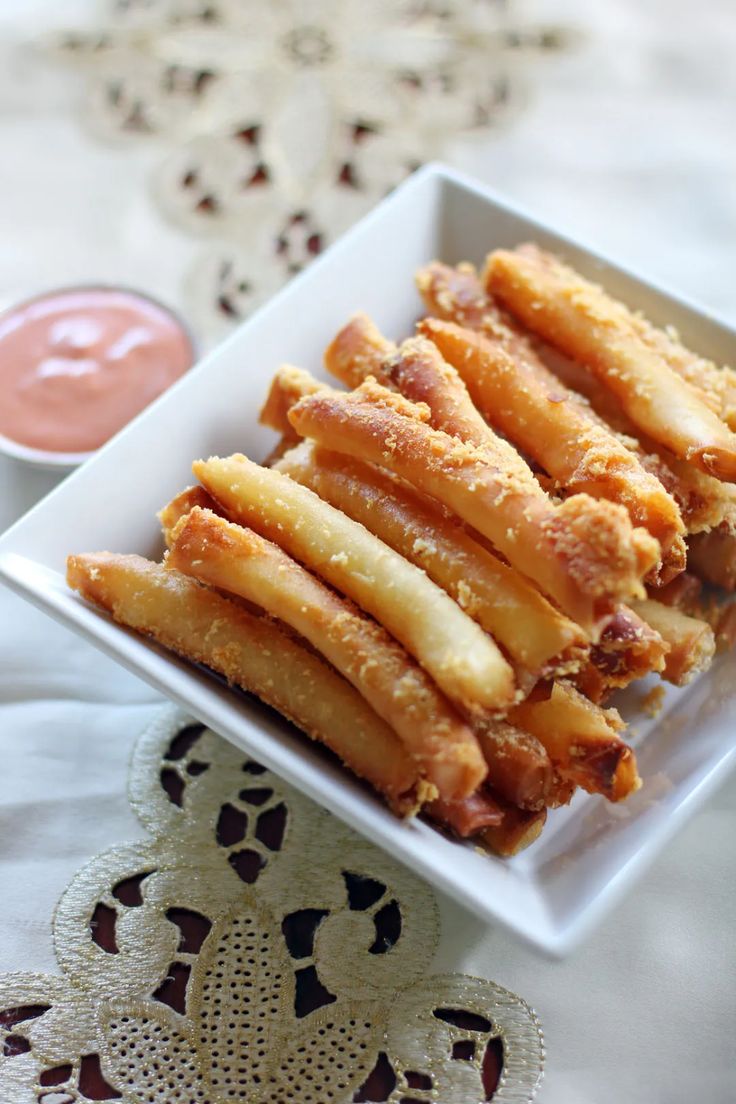 a white plate topped with french fries next to dipping sauce