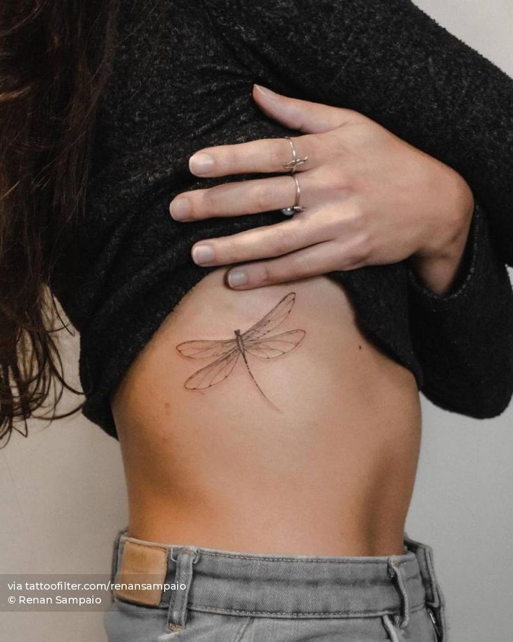 a woman's stomach with a small dragonfly tattoo on her belly and the back