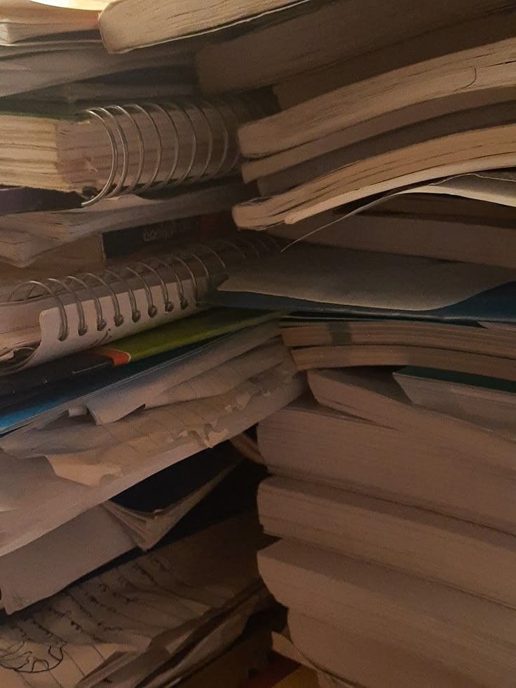 a stack of papers and pens sitting on top of each other next to a computer mouse