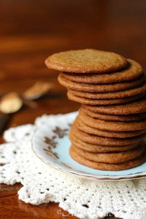 a stack of cookies sitting on top of a blue and white plate next to a crocheted doily