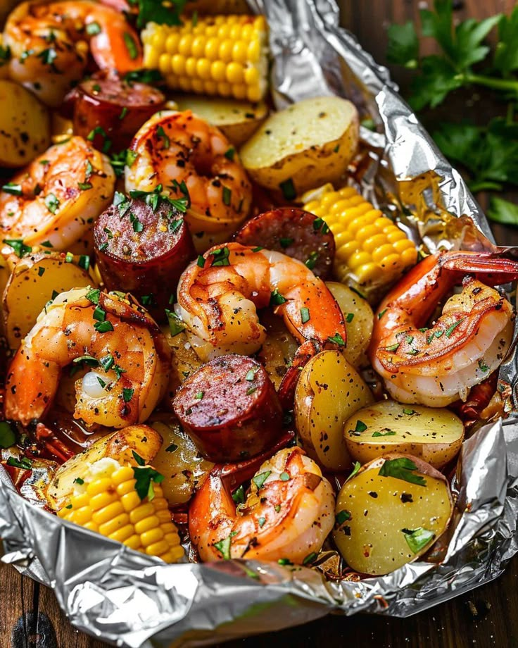 shrimp, potatoes and corn on the cob in foil with parsley garnish