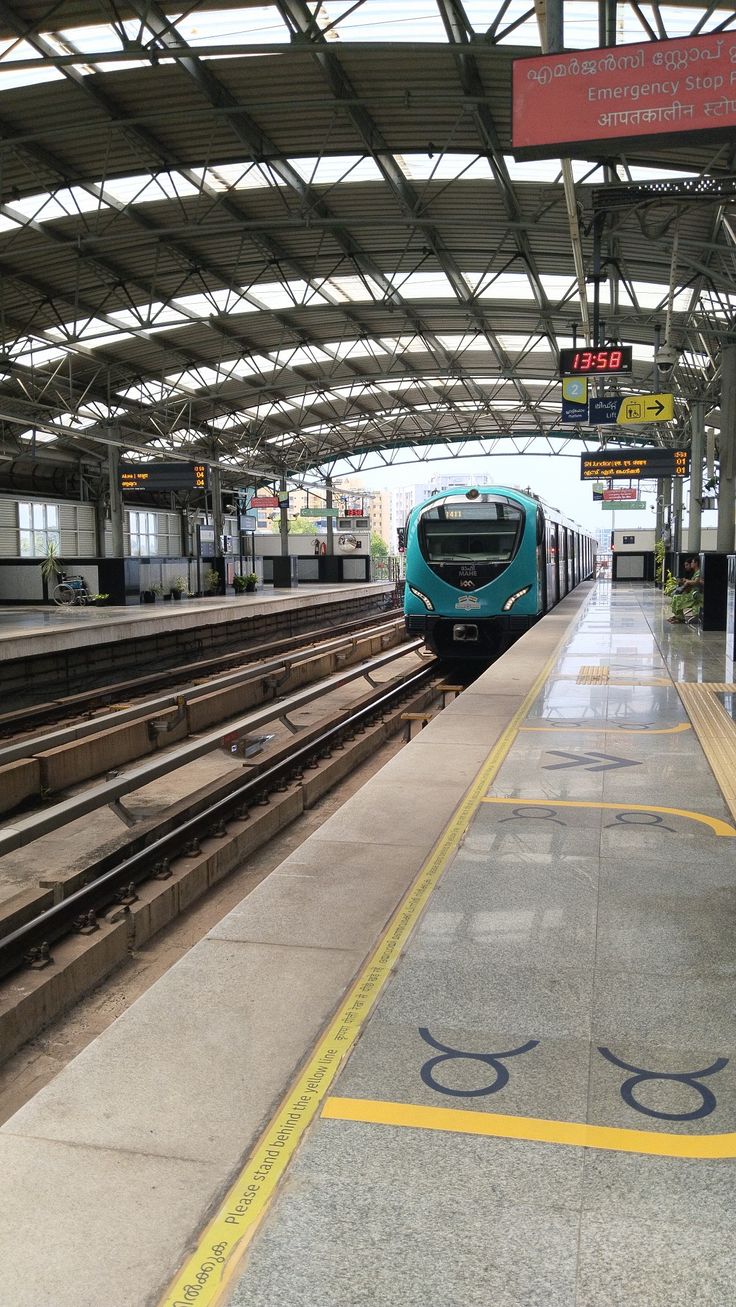 a blue train pulling into a train station next to a loading platform with no people