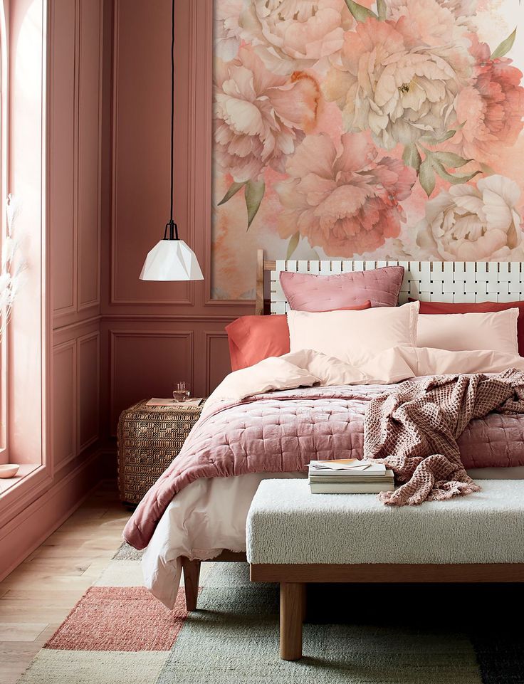 a bedroom decorated in pink and white with flowers painted on the wall behind the bed