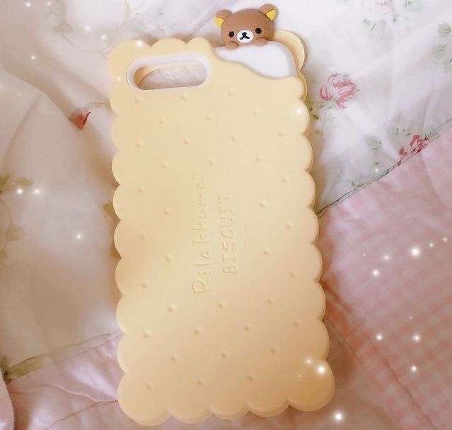 a cell phone case with a teddy bear on the front and back cover, laying on a bed