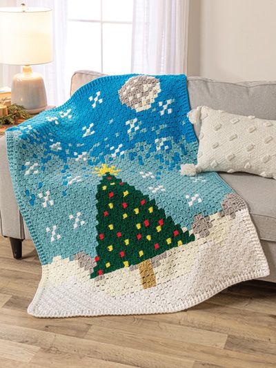 a crocheted christmas tree afghan on a couch