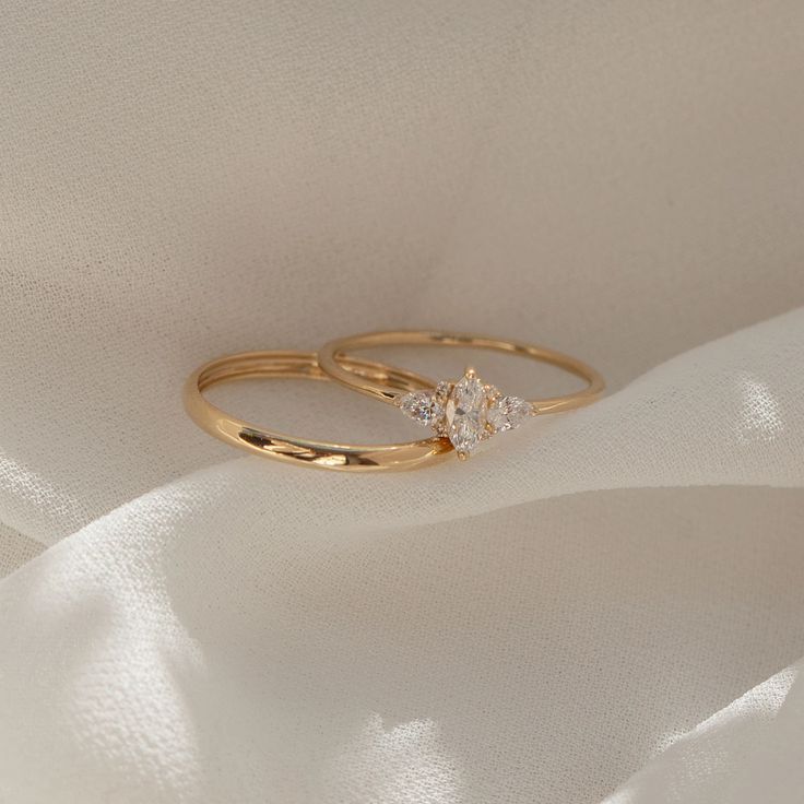 two gold wedding rings with diamond accents on white silk fabric, closeup view from above