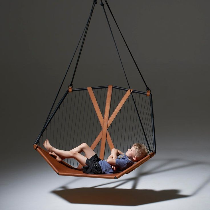 a young boy laying in a hanging chair