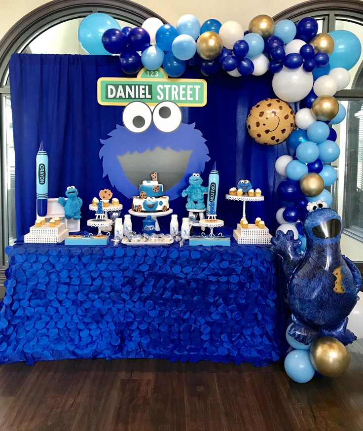 a sesame street birthday party with balloons and desserts on a table in front of a cookie monster backdrop