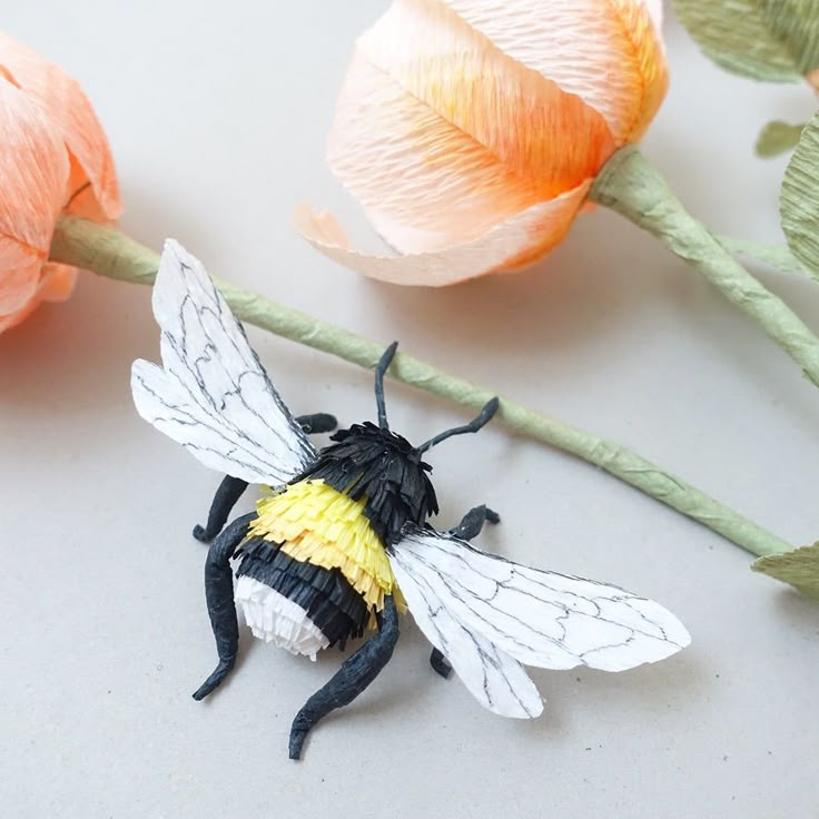 a black and yellow bee sitting on top of a flower next to some pink flowers