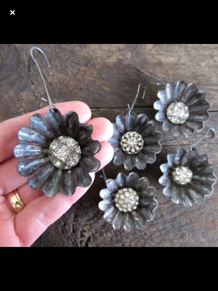 three flower shaped earrings are being held in someone's hand