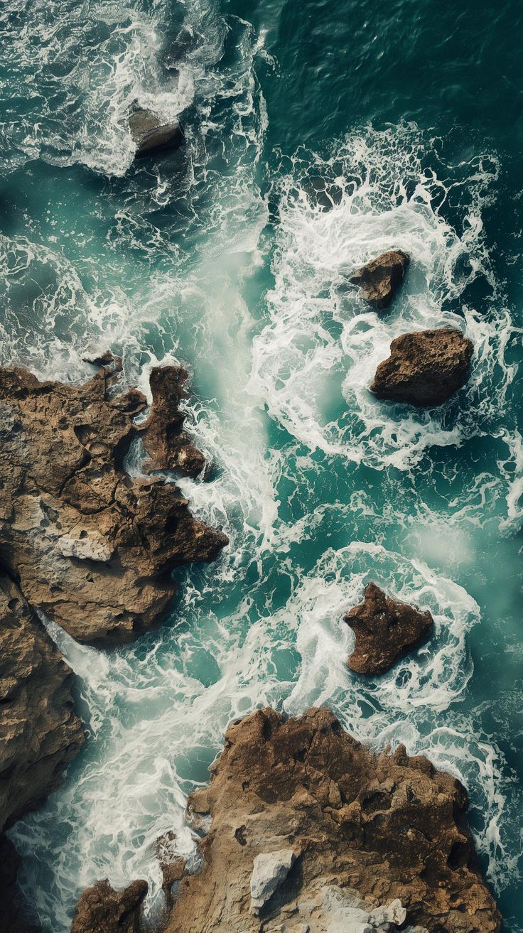 an aerial view of the ocean and rocks